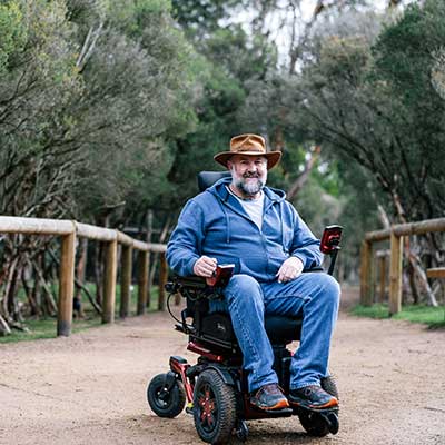 A man in a motorised wheelchair going through the wallaby walk area of Moonlit Sanctuary